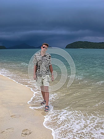 Handsome guy on an exotic beach. walk on the beach before tropical rain Stock Photo
