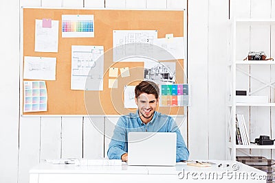 Handsome happy businessman working with laptop in office Stock Photo