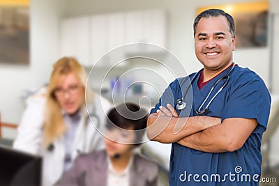 Handsome Hispanic Doctor or Nurse Standing in His Office with Staff Working Behind Stock Photo