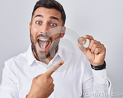 Handsome hispanic man holding polkadot cryptocurrency coin smiling happy pointing with hand and finger Editorial Stock Photo