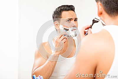Handsome Hispanic man shaving his beard Stock Photo