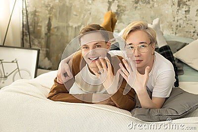 Handsome international homosexual couple who recently married relaxing in bed before night sleep and looking at camera Stock Photo