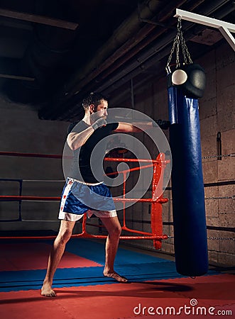 Handsome kick boxer training kicking and punching boxing bag Stock Photo