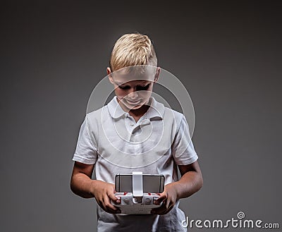 Handsome little boy boxer with blonde hair dressed in a white t-shirt holds a quadcopter control remote. Stock Photo
