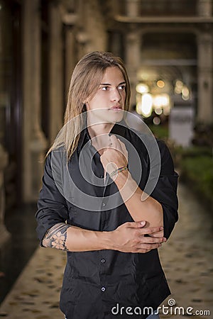 Handsome long hair young man indoors in elegant gallery Stock Photo