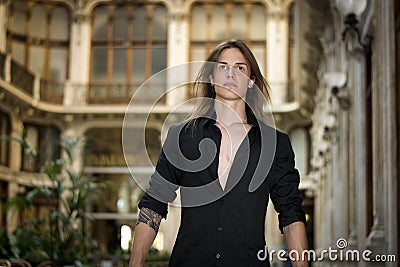 Handsome long hair young man indoors in elegant gallery Stock Photo