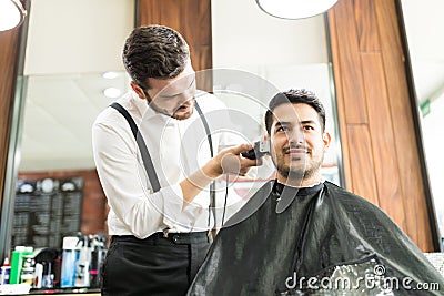 Customer Smiling While Barber Trimming His Hair In Shop Stock Photo