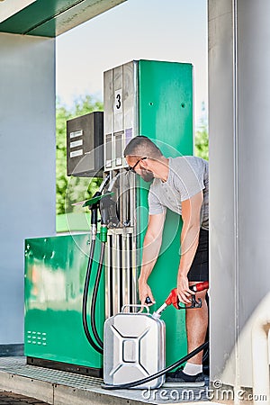 Handsome male filling canister with fuel. Stock Photo