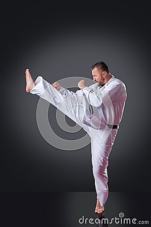 Handsome male karate player doing kick on the gray background Stock Photo