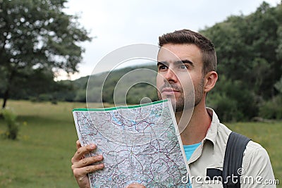 Handsome male looking at map and planning trip after getting lost alone in the woods Stock Photo