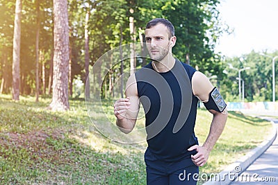 Handsome male running in park while listening to music Stock Photo