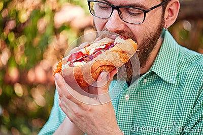 Goodly boy with a glasess tasting delicious food in the park. Nature background. Stock Photo