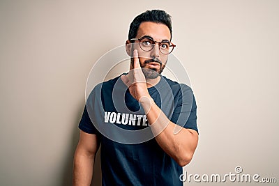 Handsome man with beard wearing t-shirt with volunteer message over white background hand on mouth telling secret rumor, Stock Photo