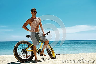 Handsome Man With Bike Sun Tanning On Beach. Summer Vacation. Stock Photo