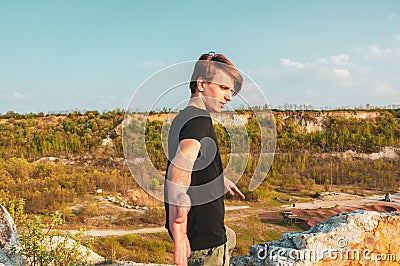 Handsome man is giving his hand in the mountains, while at the top of the cliff Stock Photo