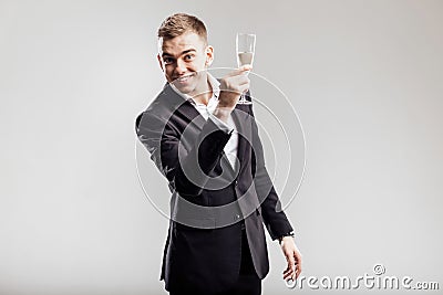 Handsome man in a business suit smiles and holds glass of champagne on a white background. Party time Stock Photo