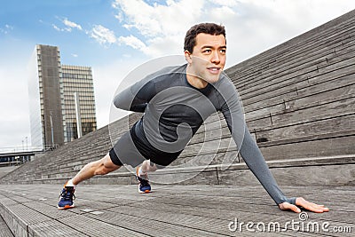 Handsome man doing push-ups on one hand outdoors Stock Photo