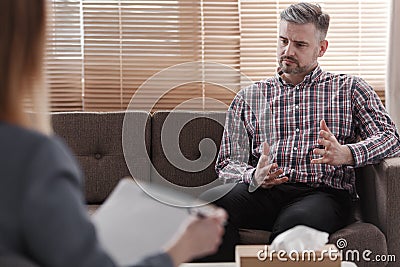 Handsome man gesticulating while talking to his psychologist during a therapy Stock Photo