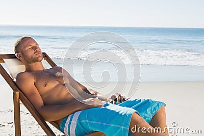 Handsome man having a nap while sunbathing on his deck chair Stock Photo