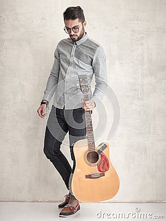 Handsome man holding an acoustic guitar against grunge wall Stock Photo