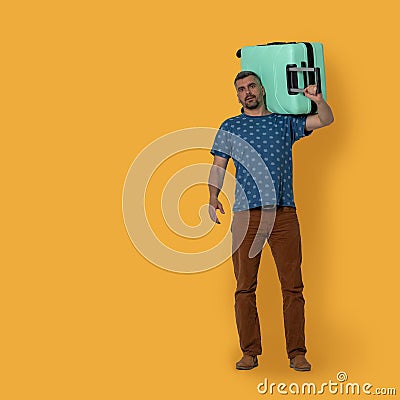 Handsome man holds plastic suitcase on his shoulder. Front view of middle-aged caucasian man holding green suitcase Stock Photo