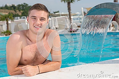 Handsome Man Leaning on the Edge of Swimming Pool Stock Photo