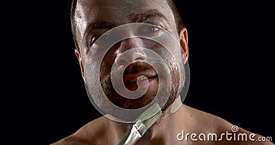 Handsome man is painting his face in white color by greasepaint, using brush, closeup Stock Photo
