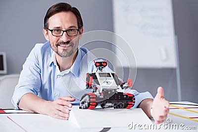 Handsome man posing with a small red robot Stock Photo