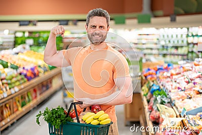 Handsome man with shopping basket with grocery. Man buying groceries in supermarket. Male model in shop. Concept of Stock Photo