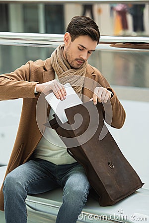 Handsome man sitting on bench and putting laptop Stock Photo