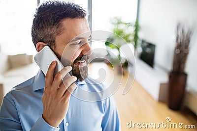 A man with a smartphone making a phone call at home. Stock Photo