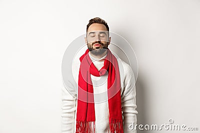 Handsome man standing with closed eyes and puckered lips, waiting for christmas kiss under mistletoe, standing over Stock Photo