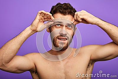 Handsome man trying to pluck his eyebrows Stock Photo
