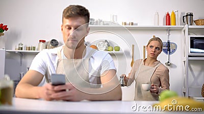 Handsome man typing message in phone, jealous wife peeping, cheating in marriage Stock Photo