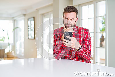 Handsome man using smartphone serious face thinking about question, very confused idea Stock Photo