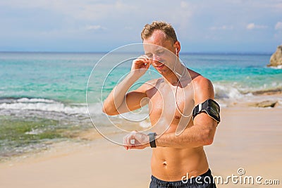 Man using wearable tech while running on the beach Stock Photo