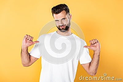 Handsome man in white t-shirt pointing with fingers at himself isolated on yellow Stock Photo