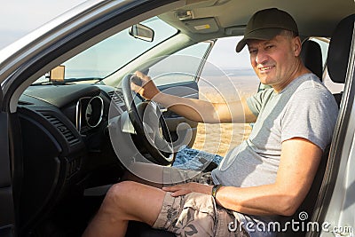 Handsome mature man sits behind the wheel in his car in nature Stock Photo