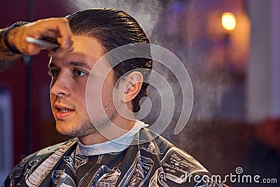 Handsome man is while having his hair cut by hairdresser at the barbershop, close up portrait. Work in the Barber shop Stock Photo
