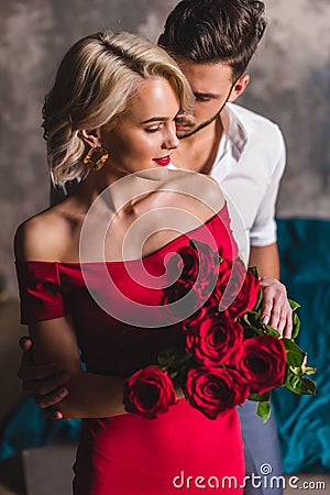 handsome man hugging smiling sensual woman in red dress holding Stock Photo