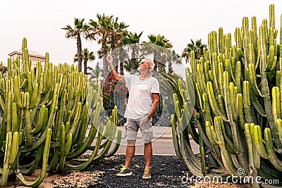 Handsome middle-aged man takes a selfie in front of a large cactus in an exotic seaside resort Stock Photo