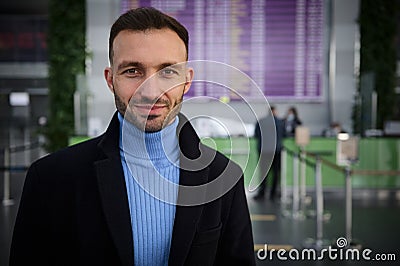 Handsome Middle-Eastern man traveler, passenger stands at flight information board with timetable in international airport arrival Stock Photo