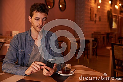 Handsome millenial in restaurant with cellphone Stock Photo