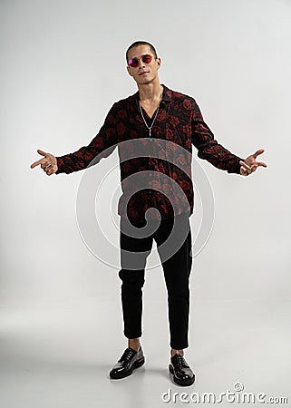 Handsome model young man in black jeans and black with red shirt and sunglasses on a gray background. Stock Photo