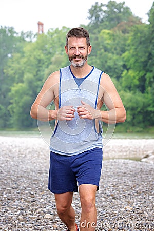 Handsome muscular bearded athlete running outdoors Stock Photo