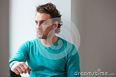 Handsome pensive young man sitting and looking at the window Stock Photo