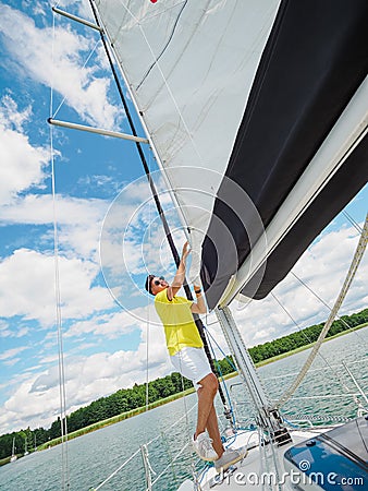 Handsome person raise the sail on a sailing yacht, summer vacations on sailboat Stock Photo