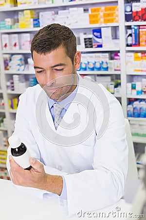 Handsome pharmacist lokking at medicines bottle Stock Photo