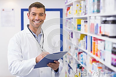 Handsome pharmacist writing on clipboard Stock Photo