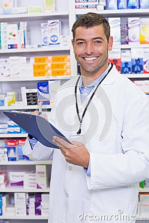 Handsome pharmacist writing on clipboard Stock Photo